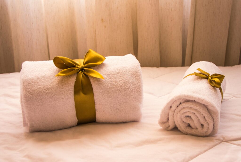 Luxurious white towels adorned with golden ribbons on a bed, creating an elegant and welcoming atmosphere.